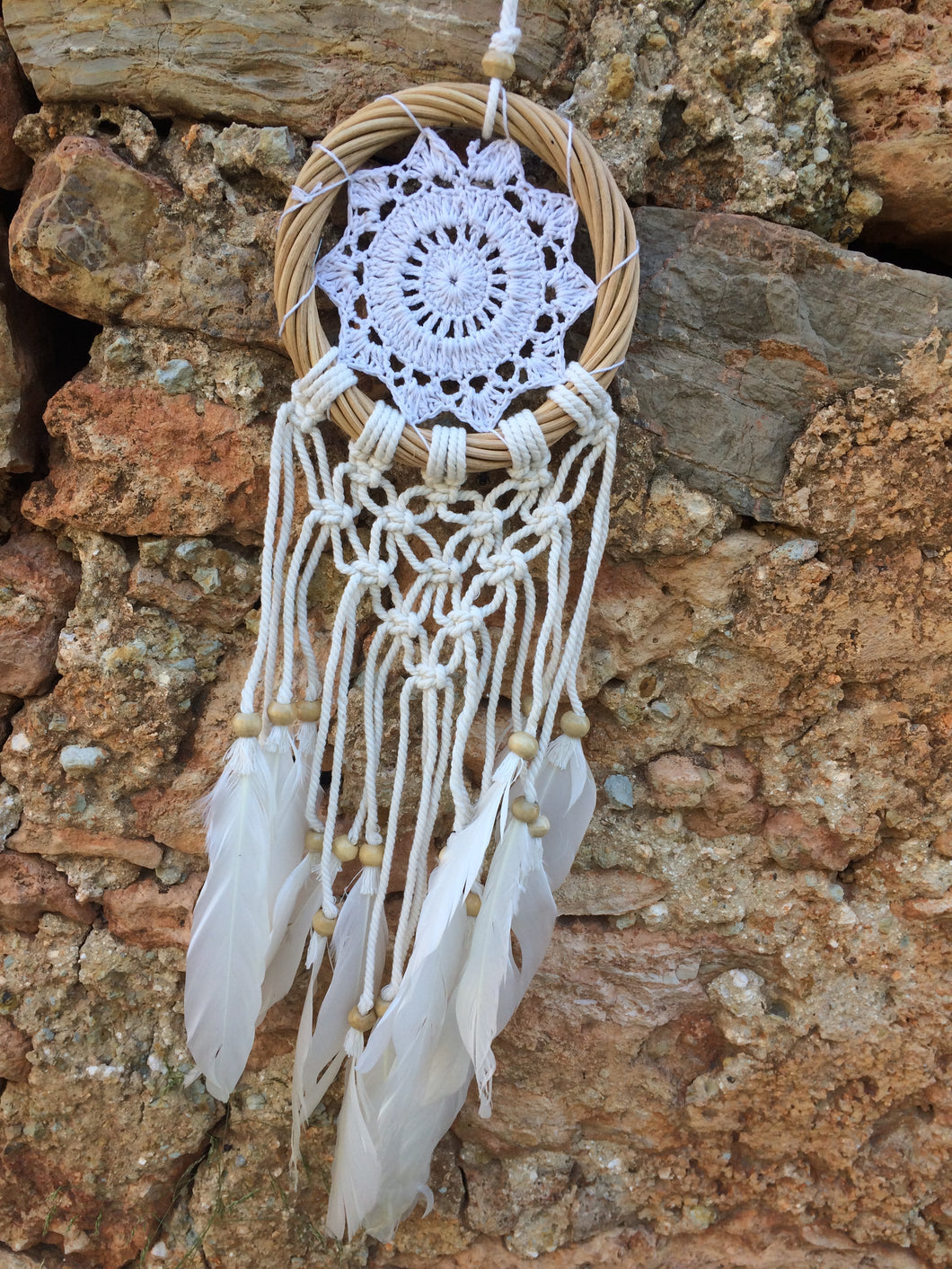 White dream catcher with feathers and wooden frame.